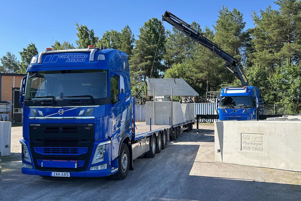 Kranbil med släp lastad med planlagerelement på gården i Katrineholm.